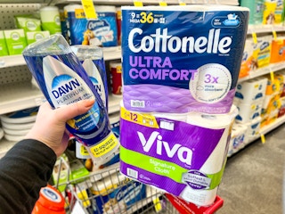 person holding 2 dawn dish soaps by a cart with viva and cottonelle