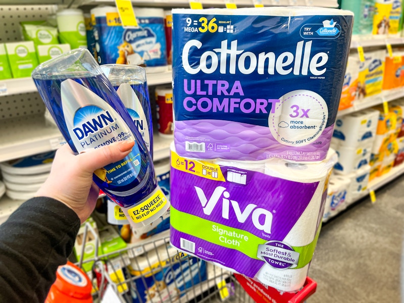 person holding 2 dawn dish soaps by a cart with viva and cottonelle