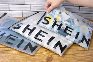 someone picking up a shein bag from a table