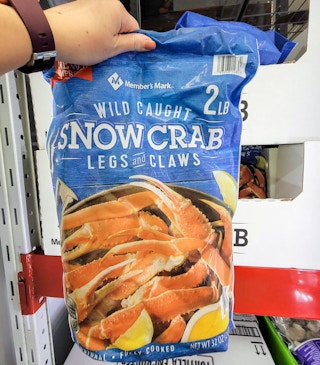 hand holding up a large bag of snow crab legs and claws