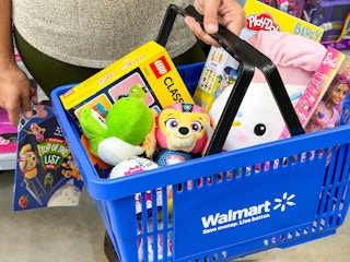 a basket full of toys with a person holding the walmart toy catalog in hand