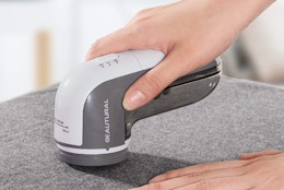 a hand using a fabric shaver on fabric