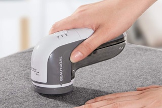 a hand using a fabric shaver on fabric