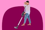 mother holding a baby while vacuuming with the iHome stick vacuum
