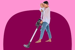 mother holding a baby while vacuuming with the iHome stick vacuum