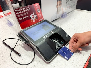 A person inserting their credit card at the credit card machine at a Target counter.