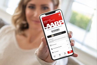 A person holding a cellphone that has a digital AARP membership card on the screen.