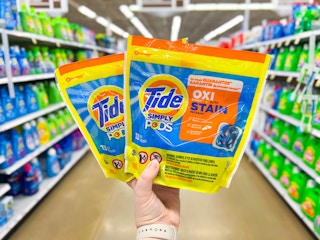 hand holding two packages of Tide pods
