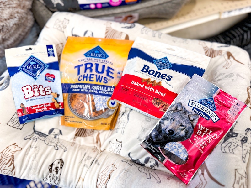 4 bags of blue buffalo dog treats on a dog bed