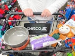 a person pushing a petco shopping cart with pet items in top part of cart
