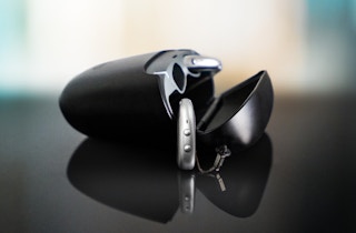 A hear dot com hearing aid with case.