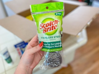 hand holding scotch brite stainless steel scrubbers in front of an amazon box