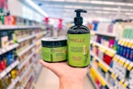 person holding a bottle of mielle shampoo and a jar of mielle hair mask in an aisle