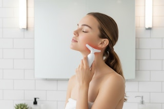 a woman using a face massager on her face