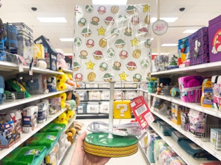 A kid's lamp held up by hand in front of a store aisle.