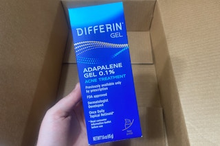 hand holding differin adapalene retinoid acne gel over an amazon box