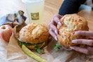 A person picking up a bagel sandwich