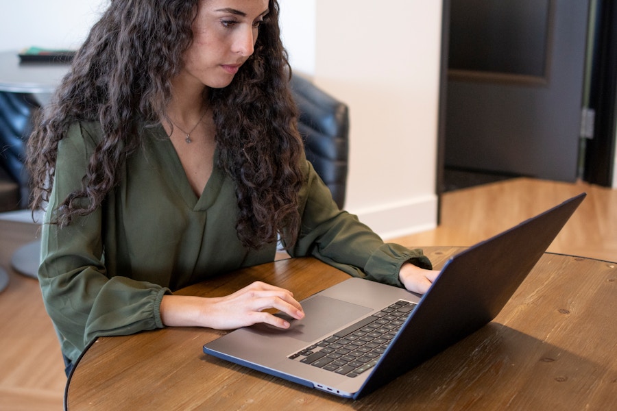 A person sitting at a table looking at a laptop computer.