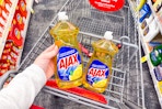 person placing ajax dish soap in a cart