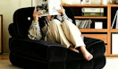 a person sitting on a foldable sofa chair reading