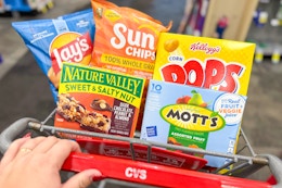 hand pushing a cvs shopping cart with snacks