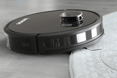 lifestyle image of a robot vacuum cleaning a rug