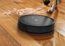 a robot vacuum on a wooden floor cleaning a pile of dirt
