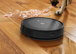 a robot vacuum on a wooden floor cleaning a pile of dirt