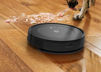 a robot vacuum on a wooden floor cleaning a pile of dirt