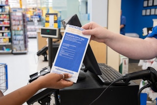 someone handing a prescription to someone at walmart