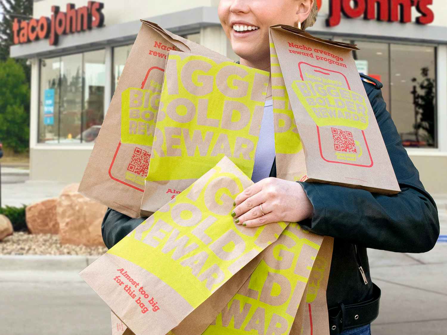 person with taco johns bags that say bigger bolder rewards