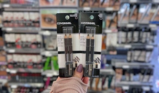 hand holding two packs of Covergirl eye pencils