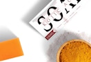 a bar of soap next to a bowl of turmeric 