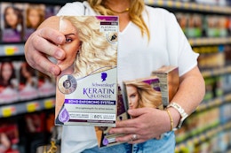 a woman holding schwarzkopf keratin blonde hair dye in walmart