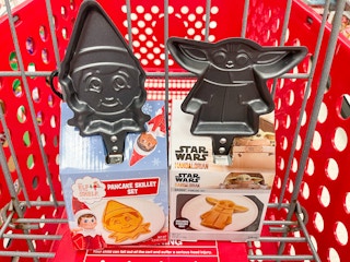 An Elf on the shelf and a Yoda Pancake Skillet Set sitting in a store cart.