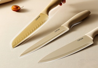 hand picking up a Carote knife set and two others laying on the table