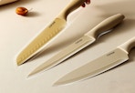 hand picking up a Carote knife set and two others laying on the table