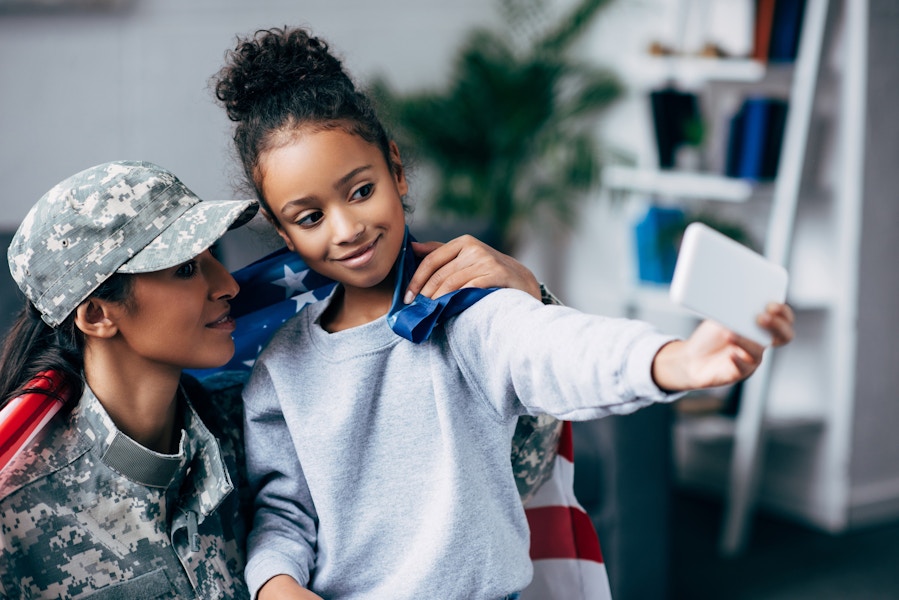 Mother in military uniform holding daughter and taking a selfie together