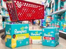 3 pampers boxes sitting a floor in front of parked target cart