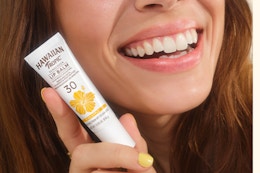 woman holding lip balm up to cheek