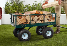 person putting wood in a garden wagon