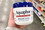 hand holding a jar of aquaphor healing ointment