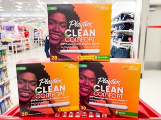 Three boxes of Playtex tampons stacked in a Target shopping cart