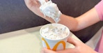 Someone taking a spoonful from a Peanut Butter Crunch McFlurry at McDonald's