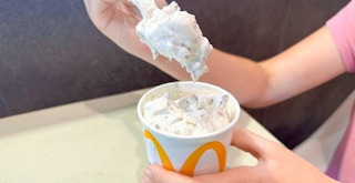 Someone taking a spoonful from a Peanut Butter Crunch McFlurry at McDonald's