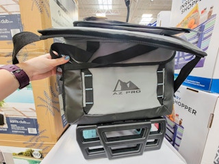 hand holding up a grey collapsible rolling cooler