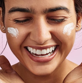a woman putting sunscreen on her face