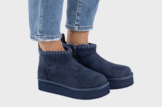 Navy pair of Muk Luks Augie Booties (woman wearing them with a pair of jeans)