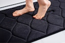 Lifestyle image of the black Smiry memory foam bath mat (close up shot of someone standing on it)