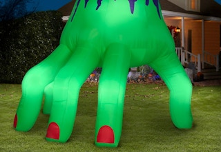A green zombie hand inflatable in a staged yard